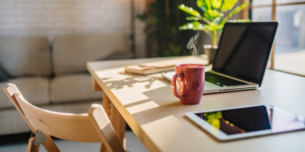 desk with cup, ipad, and laptop